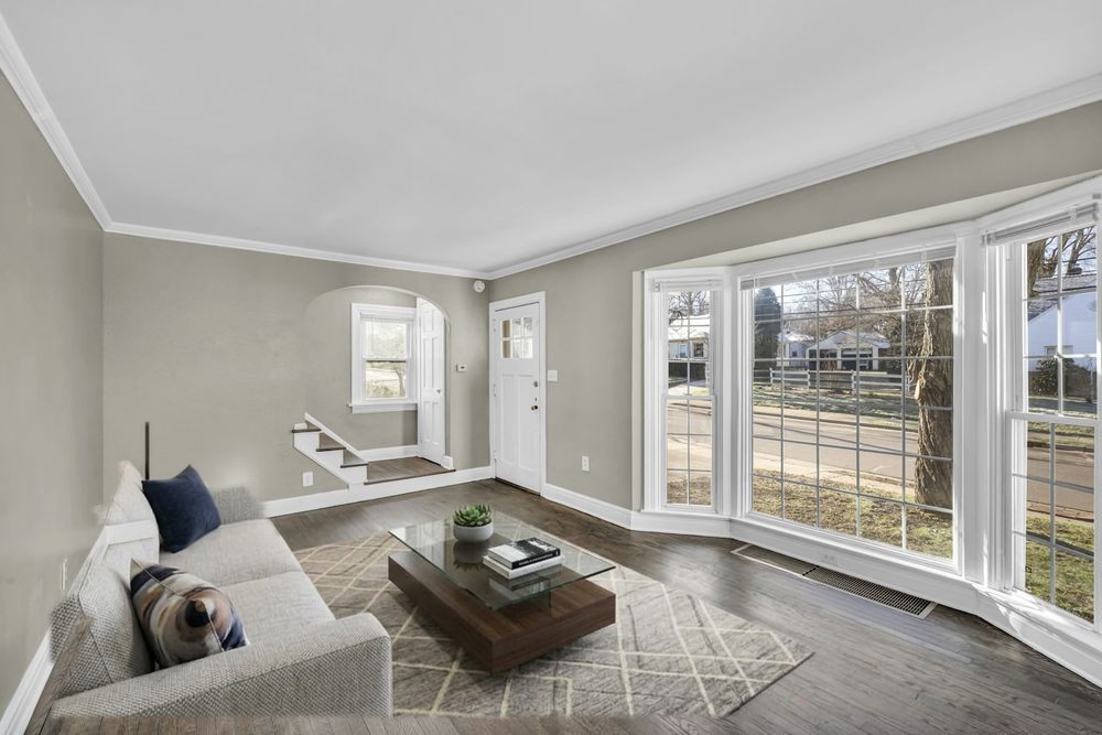 Living room virtually staged by RoomFilled: sofa, rug and coffee table added, walls and bay window untouched